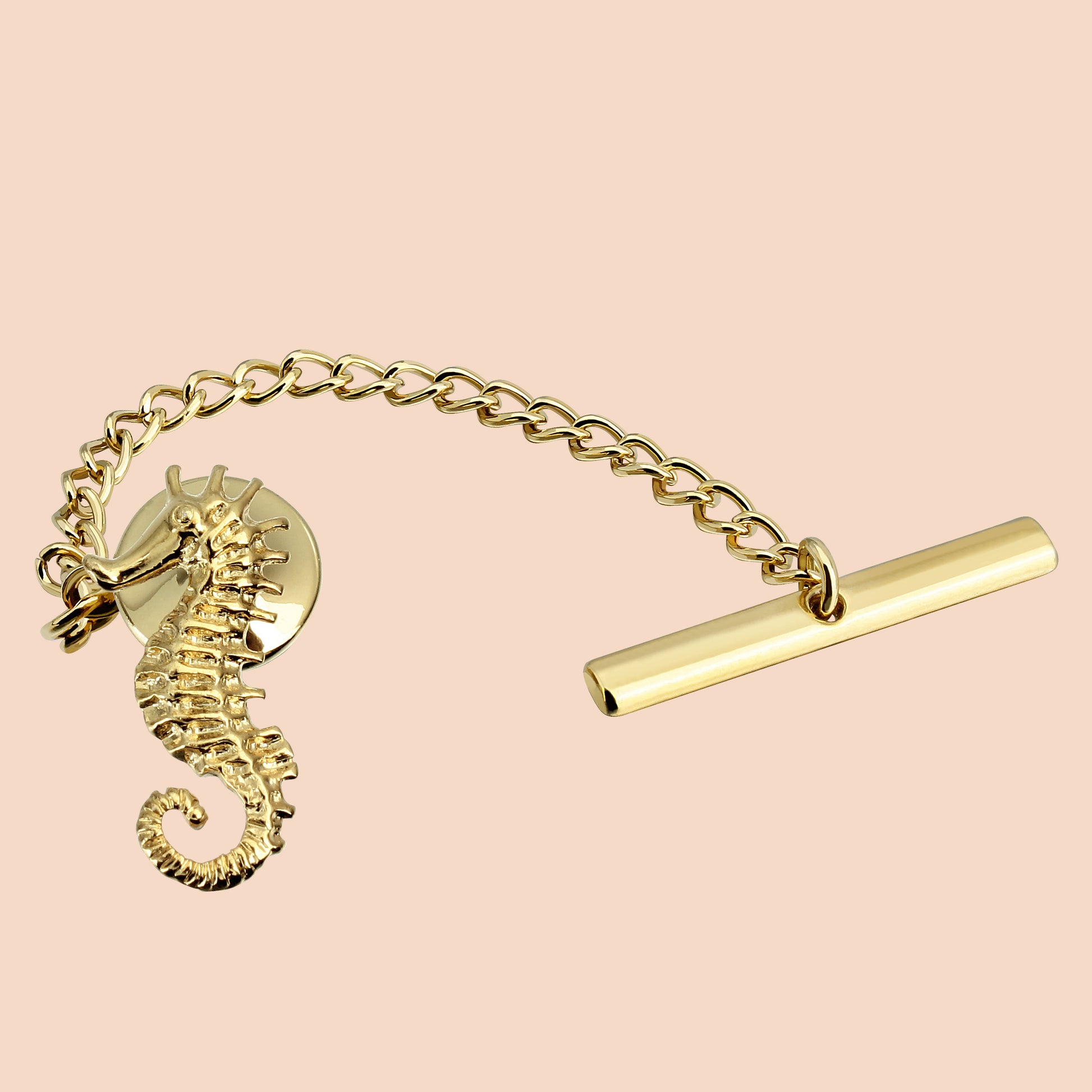 A gold-colored seahorse-shaped tie tack with a chain and a metallic clasp.
