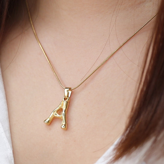 Gold-tone initial pendant necklace worn for a personalized everyday look