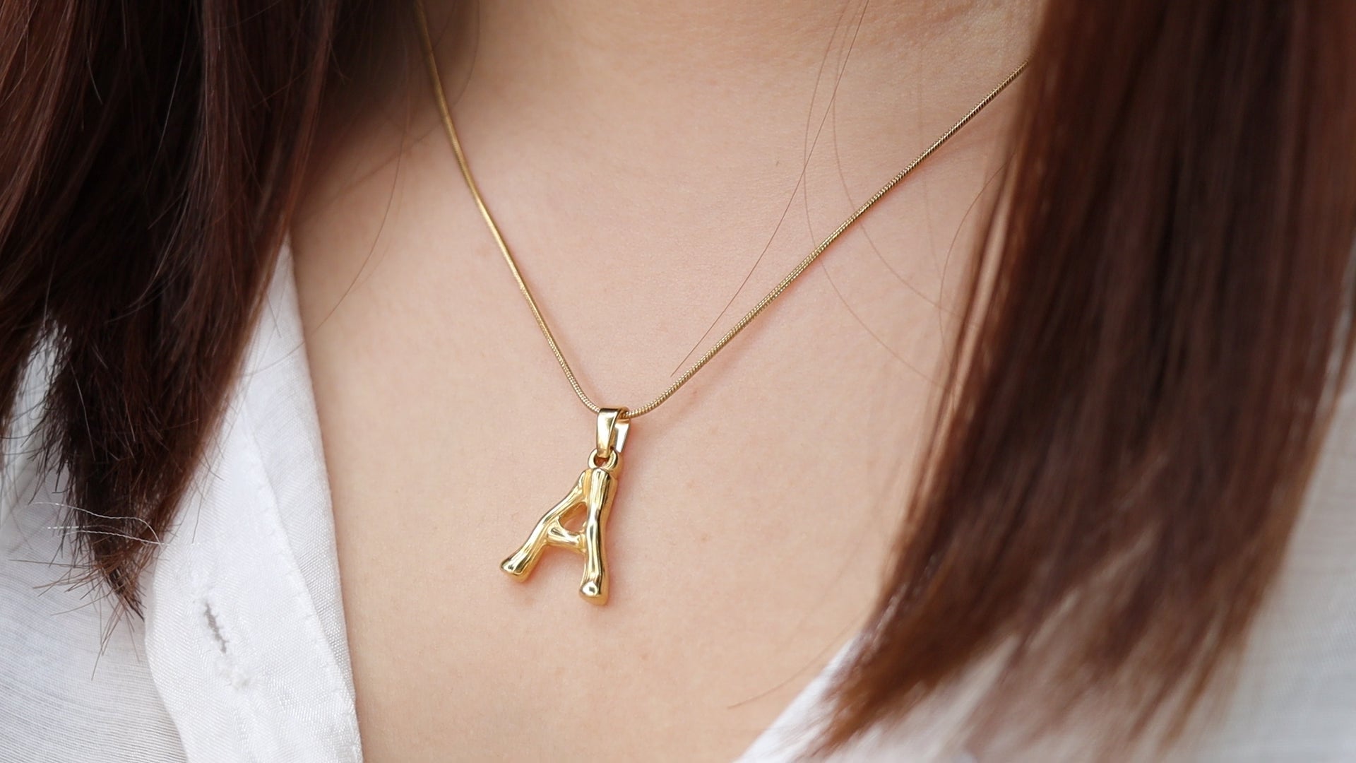 Gold-tone initial pendant necklace worn for a personalized everyday look